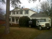 Summit Roofing, LLC team working on a residential roof with their truck parked in front to throw debris into